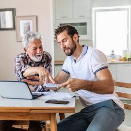 A man helping a senior with documents.